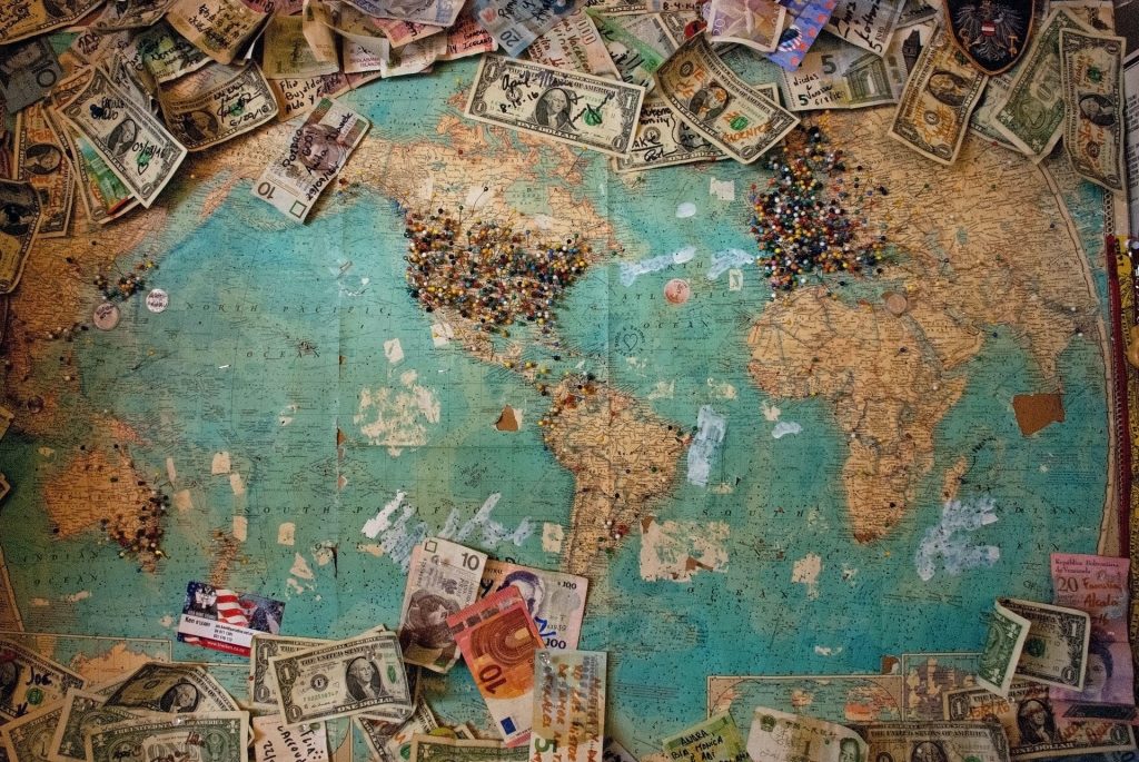 A map of the world with different currencies and money surrounding it.