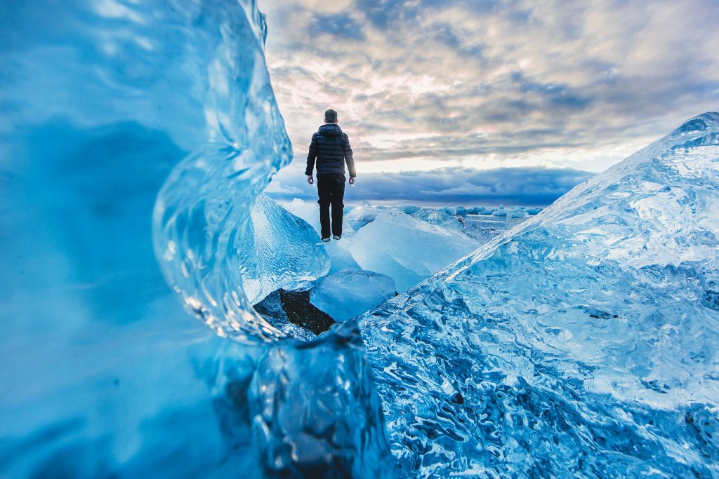 Photo of a person stood on a glacier, looking out towards a sunrise / sunset. Image used to illustrate blog post on why The Better Business Network supports ClientEarth.