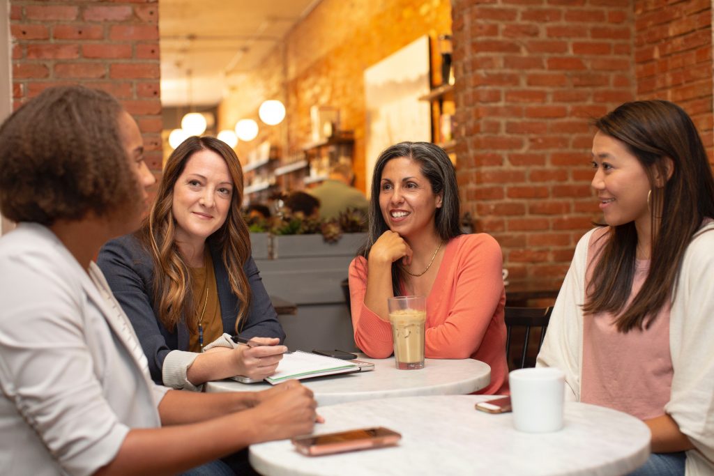 image of women around 2 mini tables talking over coffee and tea