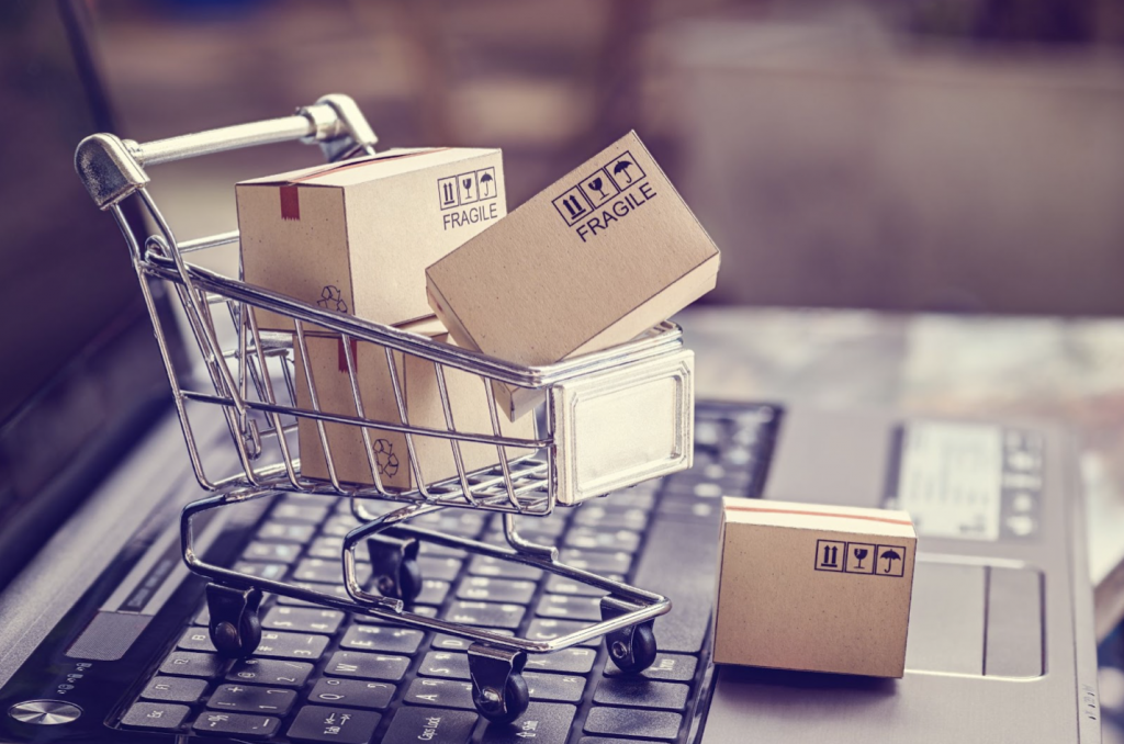 image of a small shopping cart with boxes falling out while on top of a laptop